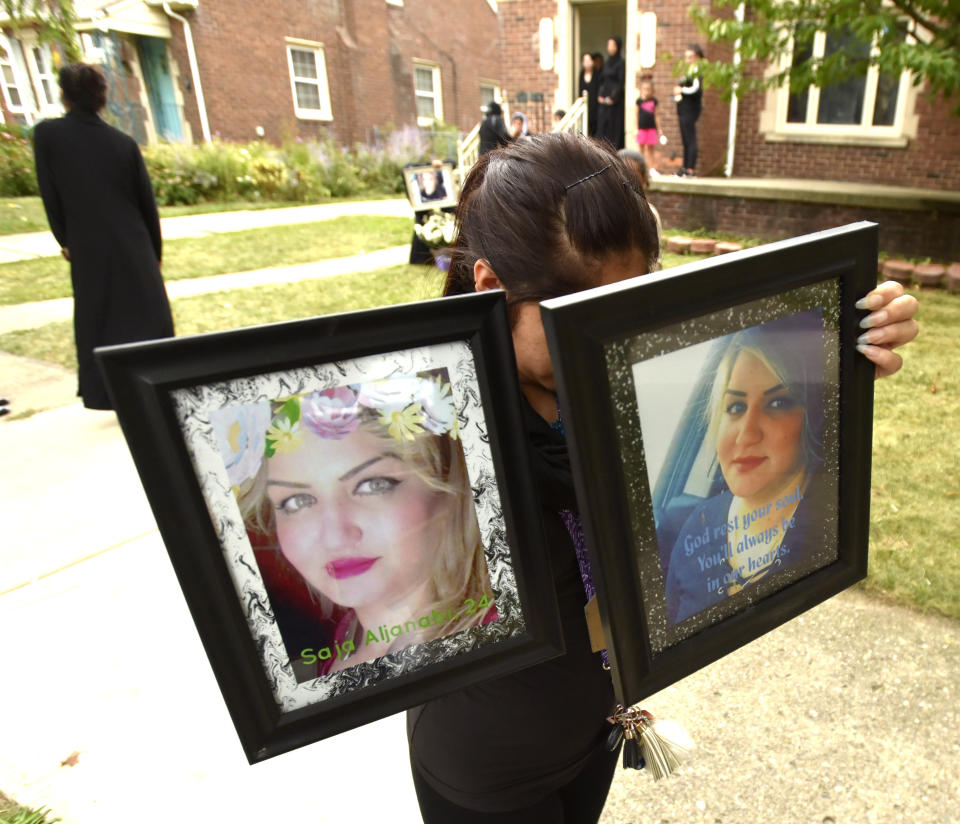 A woman who wishes not to be identified carries portraits of Saja Aljanabi to her makeshift memorial on Bingham St., in Dearborn, Mich., Sunday, Sept. 8, 2019. Dearborn Police Chief Ronald Haddad said Thursday, Sept. 12, 2019, that the 14-year-old, a 13-year-old and 17-year-old are being held in connection with last week's killing of Saja Aljanabi and they could be involved in other crimes in the area. (Todd McInturf/Detroit News via AP)