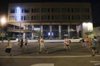 Runners pass the new Hotel Tupelo on Main Street as they hold their "Liza's Lights" run early Friday morning, Spet. 9, 2022, in Tupelo Miss., to remember Eliza Fletcher, who was abducted and murdered while she was running in the early morning hours in Memphis, Tenn. (Thomas Wells/The Northeast Mississippi Daily Journal via AP)