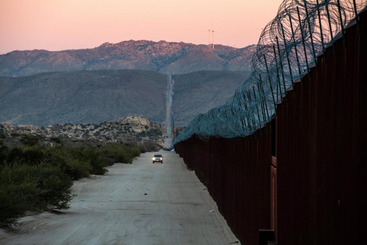 <span>A car drives alongside the border fence at the US-Mexico border in California on 6 December 2023.</span><span>Photograph: Valérie Macon/AFP via Getty Images</span>