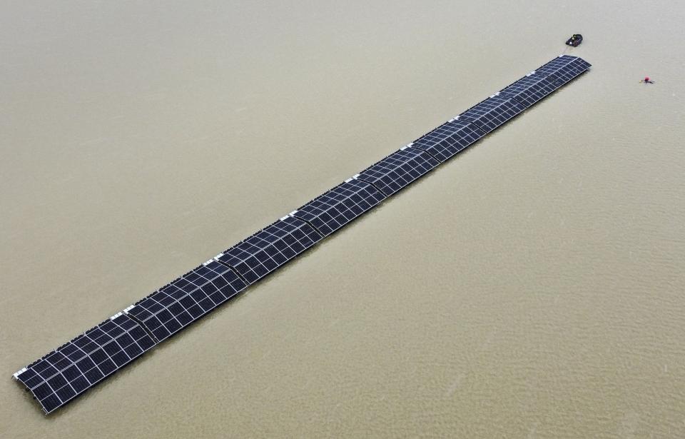 FILE - Solar panels are pulled by a boat to a floating photovoltaic plant on a lake in Haltern, Germany, April 1, 2022. Floating solar panel farms are attractive not just for their clean power and lack of a land footprint, but because they also conserve water by preventing evaporation. (AP Photo/Martin Meissner, File)