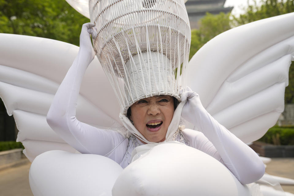 Artist Kong Ning makes a face as she adjusts the head gear of her "Transparent Earth" wearable installation, in commemoration of Earth Day in Beijing, China, April 22, 2024. (AP Photo/Tatan Syuflana)