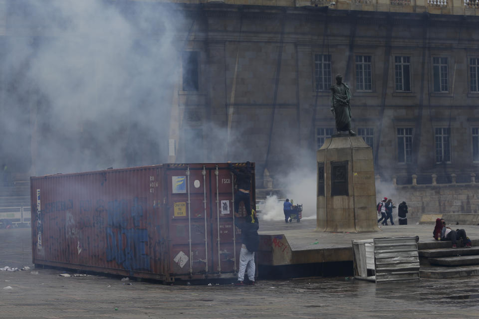 Anti-government protesters climb on a containers in front of Congress in Bogota, Colombia, Friday, Nov. 22, 2019. Colombian President Iván Duque ordered a curfew in the nation's capital amid continuing unrest one day after tens of thousands of people took to the streets in demonstrations during a nationwide strike. (AP Photo/Ivan Valencia)