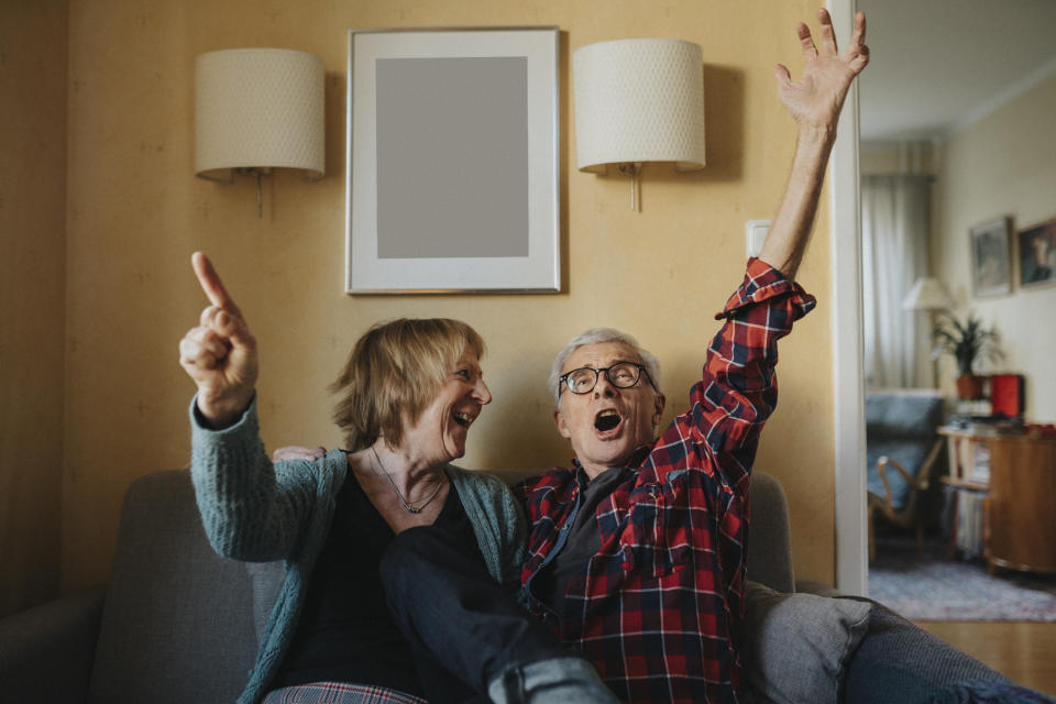 Senior couple sitting on sofa and singing pension