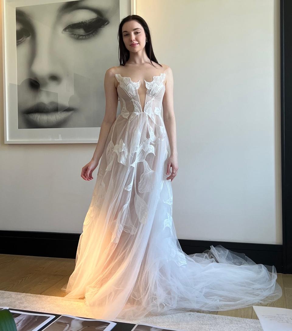 A woman poses in a wedding dress covered in flowers.