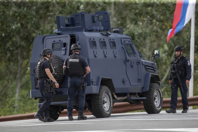 Agentes de policía de Kosovo vistos cerca de un vehículo blindado aseguran un cruce de caminos que conduce al Monasterio de Banjska en la aldea de Banjska el domingo 24 de septiembre de 2023.