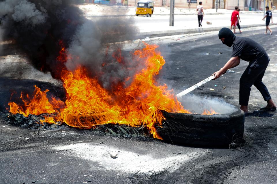Protesters burn tires to block roads during a demonstration demanding the return of electricity in Basra, southeast of Baghdad, Iraq, Friday, July 2, 2021. A widespread power outage is hitting Iraq as temperatures reach scorching levels, affecting even affluent areas in the capital and stirring concerns of widespread unrest. (AP Photo/Nabil al-Jurani)