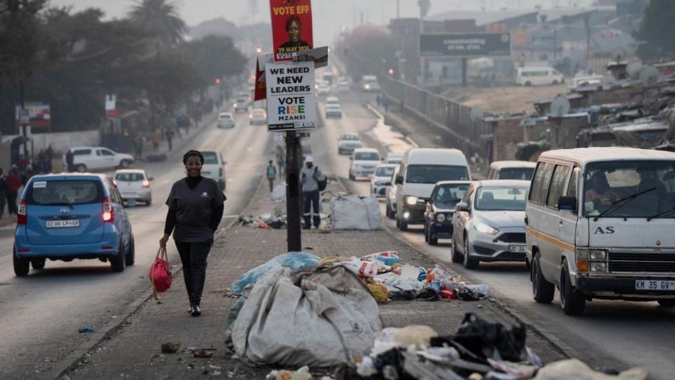 A woman walks past piles of uncollected rubbish in Alexandra township, a day before national elections in Johannesburg, South Africa, May 28, 2024