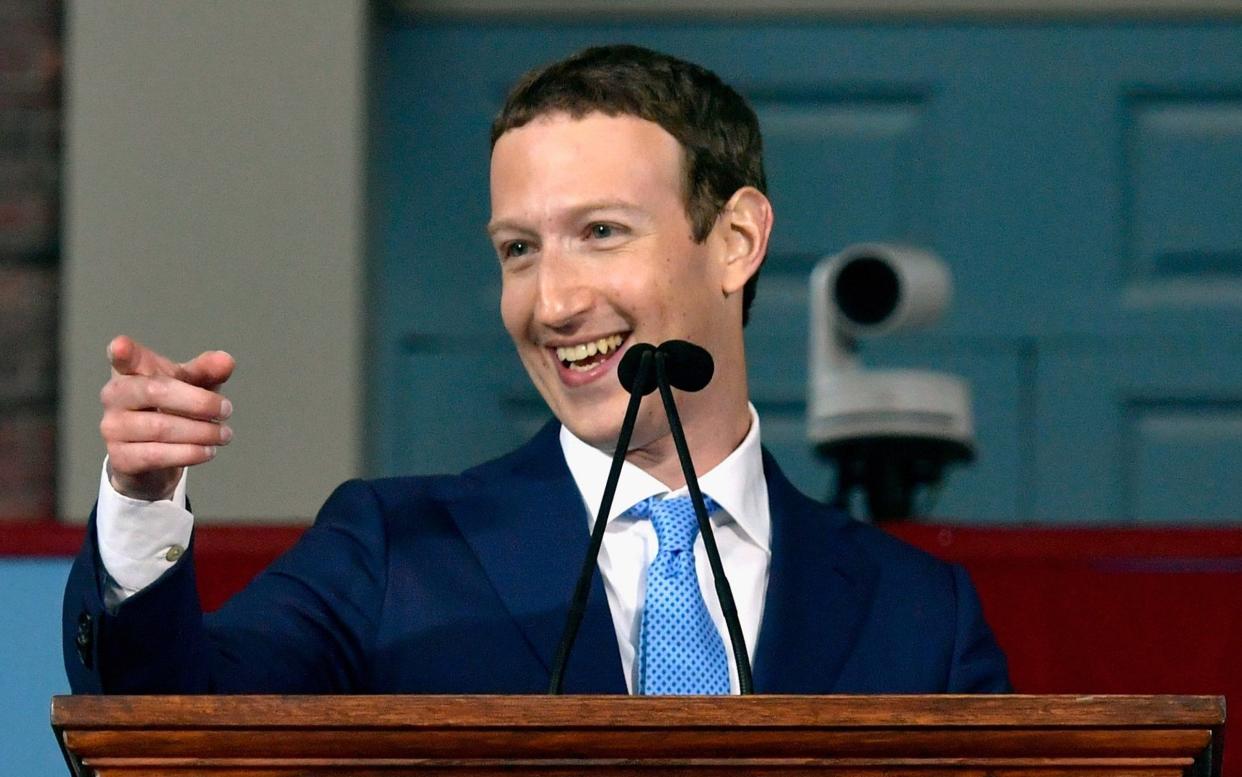 Mark Zuckerberg, wearing a navy blue suit and light blue silk tie, grins as he points to something off camera - Paul Marotta/Getty