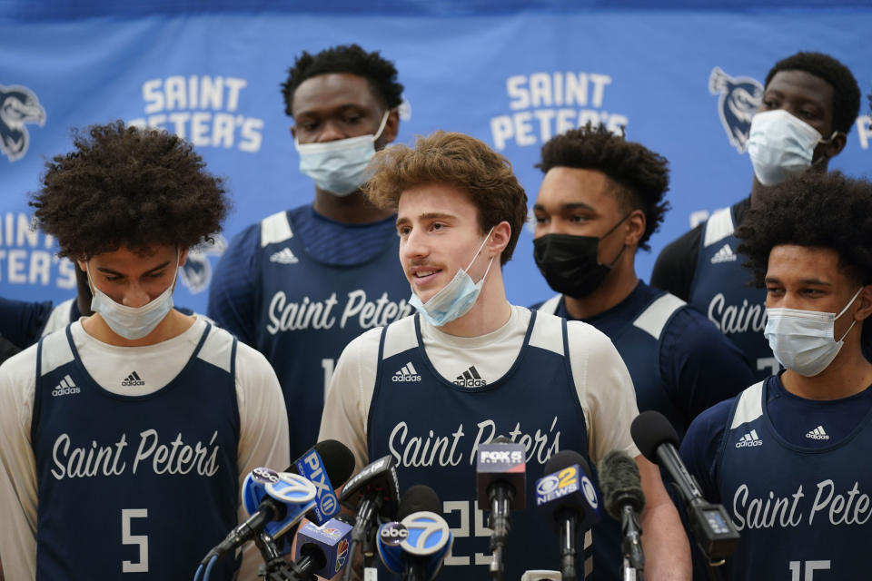 Surrounded by teammates, St. Peter's Doug Edert, center, speaks to reporters before NCAA college basketball practice in Jersey City, N.J., Tuesday, March 22, 2022. (AP Photo/Seth Wenig)