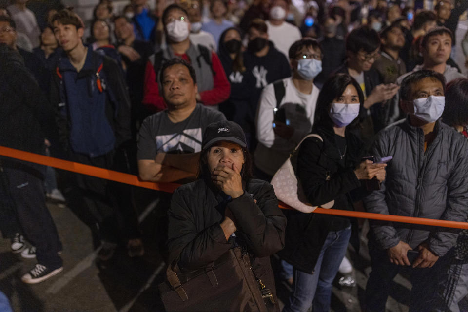 Residents and others look on as a fire burns at a construction site in Hong Kong, Friday, March 3, 2023. The fire erupted at the site of The Mariners’ Club redevelopment project in the densely populated Tsim Sha Tsui district at about 11 p.m. on Thursday night. (AP Photo/Louise Delmotte)