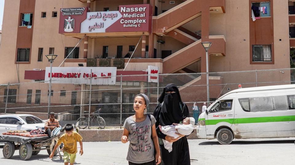 PHOTO: A girl walks with a woman carrying an infant child outside Nasser Medical Complex in Khan Yunis in the southern Gaza Strip, June 18, 2024. (Bashar Taleb/AFP via Getty Images)