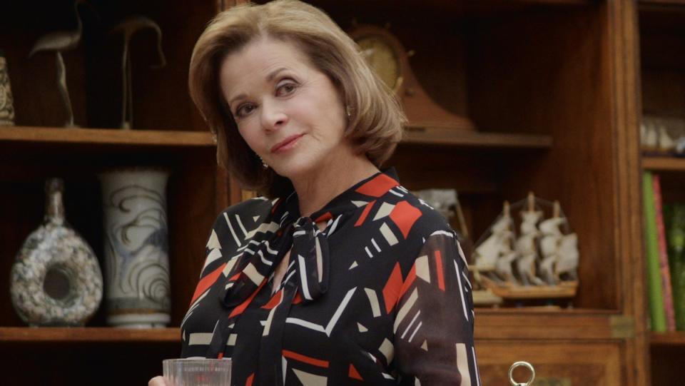 Jessica Walter as Lucille Bluth holding a glass in front of a bookcase on Arrested Development.