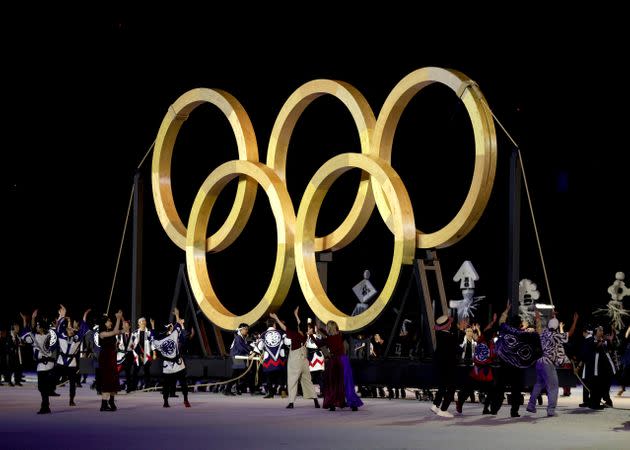 Performers dance in front of giant golden Olympic Rings. (Photo: Hannah McKay - Pool via Getty Images)