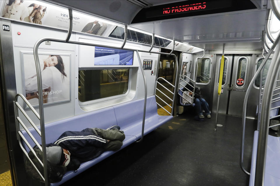 FILE - In this May 6, 2020 file photo, homeless people sleep on a train at the Coney Island Stillwell Avenue Terminal in the Brooklyn borough of New York. New York City transit officials said they're providing buses for homeless people to shelter from unseasonably frigid temperatures this weekend during newly instituted overnight subway closures. The subway system has been shutting down from 1 to 5 a.m. since Wednesday, May 6, as part of an outbreak-related plan for daily train disinfecting. (AP Photo/Frank Franklin II, File)