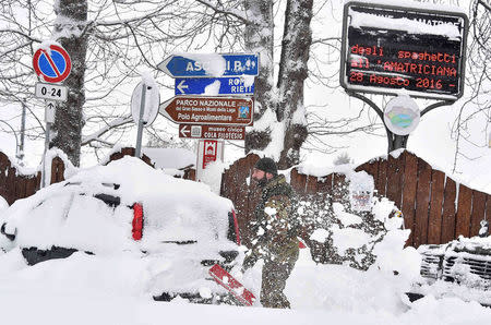 A soldier removes snow in Amatrice, after a series of earthquakes hit the town and parts of central Italy, January 18, 2017. REUTERS/Emiliano Grillotti