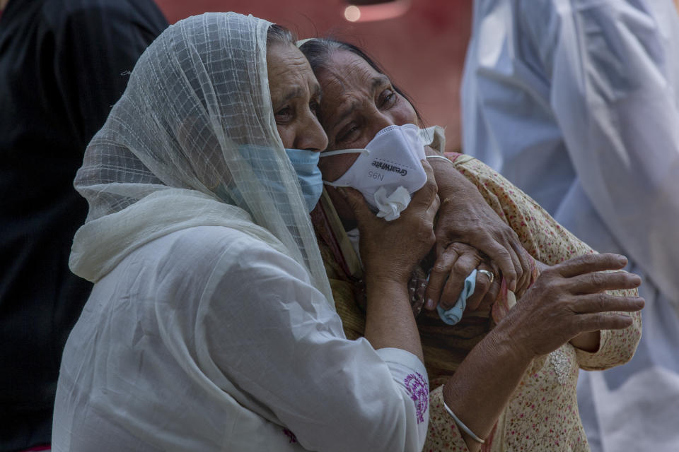 FILE - In this May 28, 2021, file photo, a relative comforts grieving family member of a person who died of COVID-19, at a crematorium in Srinagar, Indian controlled Kashmir. The latest alarming coronavirus variant — the delta variant, first identified in India — is exploiting low global vaccination rates and a rush to ease pandemic restrictions, adding new urgency to the drive to get more shots in arms and slow its supercharged spread. (AP Photo/Dar Yasin, File)