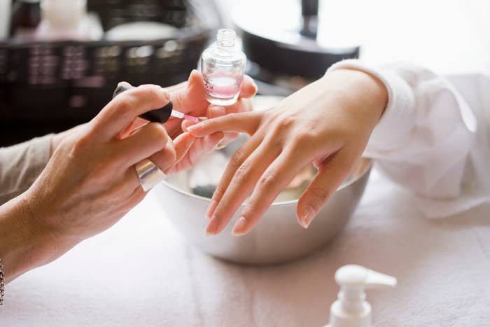 A person is having their fingernails painted, possibly preparing for a wedding ceremony