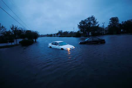 An abandoned car's hazard lights continue to flash as it sits submerged in a rising flood waters during pre-dawn hours after Hurricane Florence struck in Wilmington, North Carolina, U.S., September 15, 2018. REUTERS/Jonathan Drake