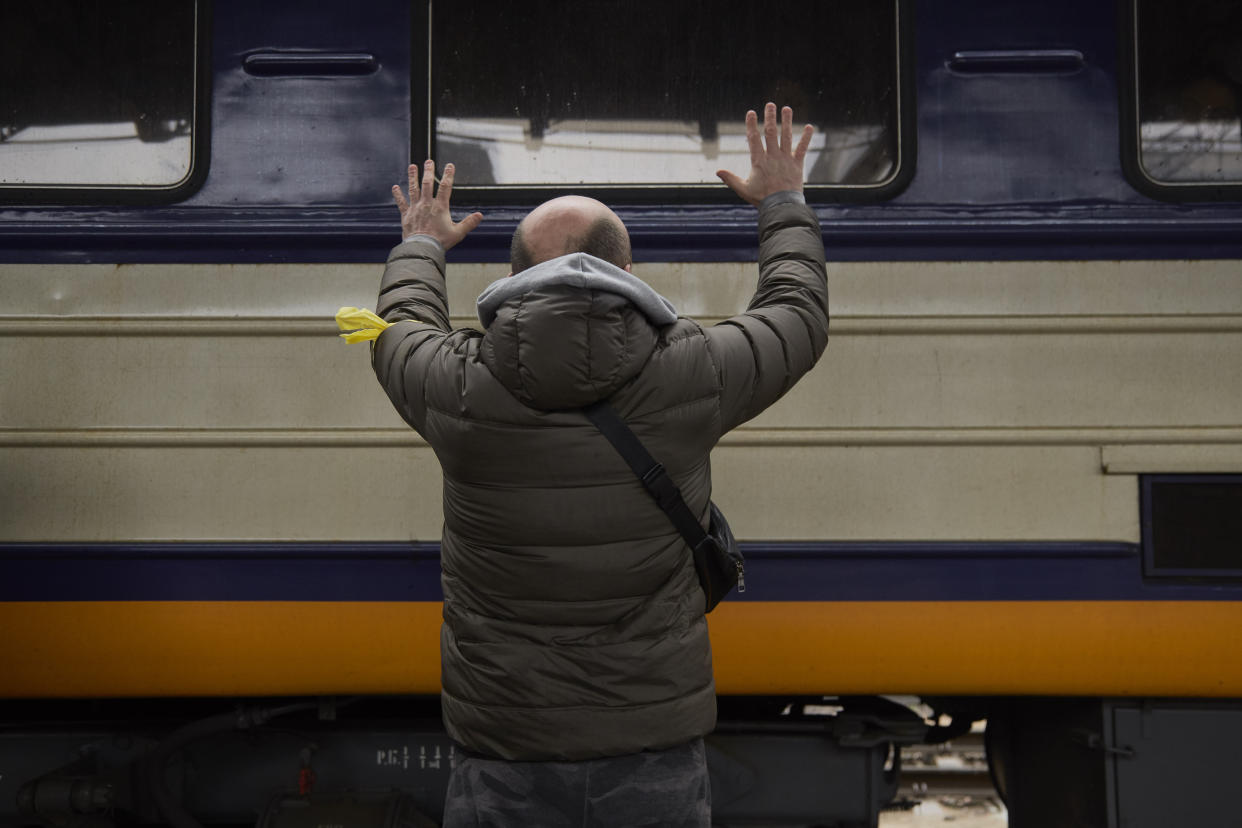 A member of the Ukrainian militia waves goodbye to his family evacuating Kyiv by train on Thursday. 