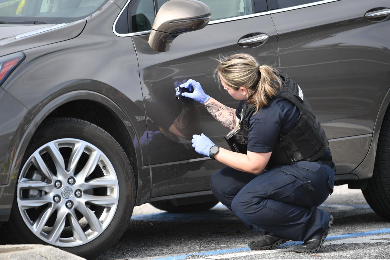 A crime scene technician from the Sarasota Police Department places an evidence sticker next to a bullet hole in a car door Friday, Jan. 19, 2024. One person died in the shooting in front of the U.S. Post Office at Sarasota Commons shopping center on North Beneva Road.