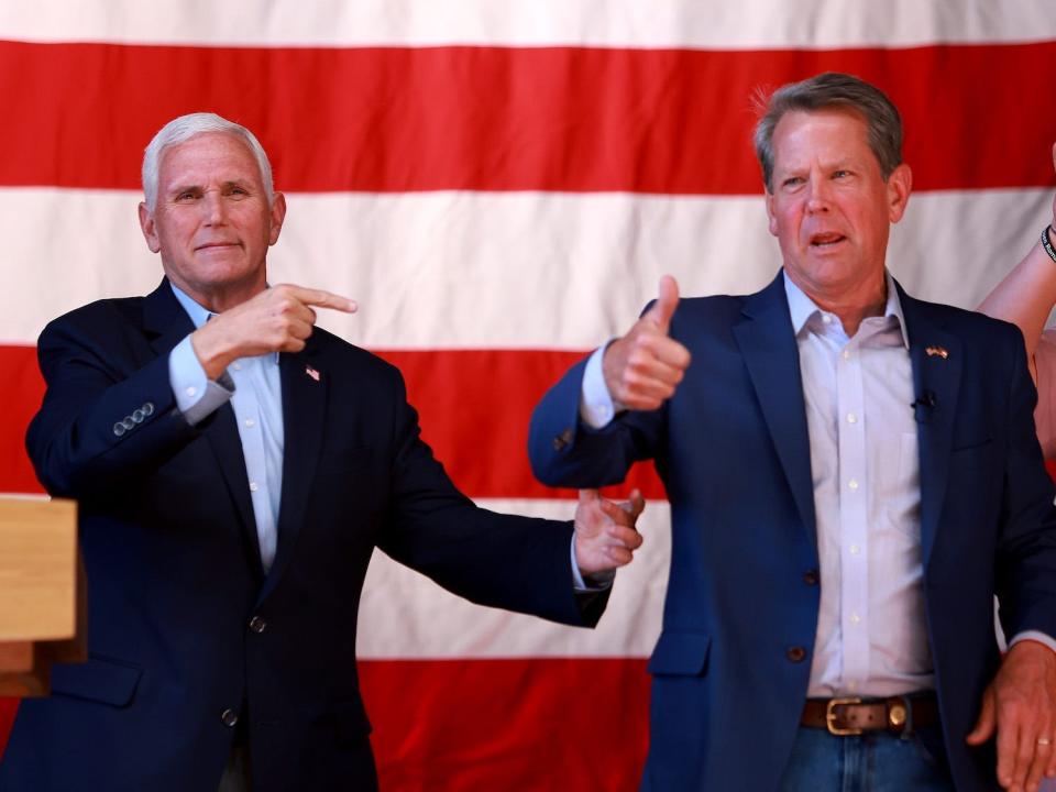 Former US Vice President Mike Pence points with his right hand towards Georgia Gov. Brian Kemp, who is giving a thumbs up, as the two men stand in front of an American flag during a primary eve rally in Kennesaw, Georgia on May 23.