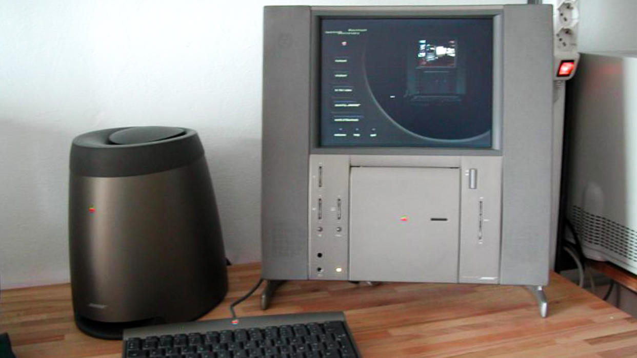 A Twentieth Anniversary Macintosh computer (right), a subwoofer (left), and a keyboard (front).