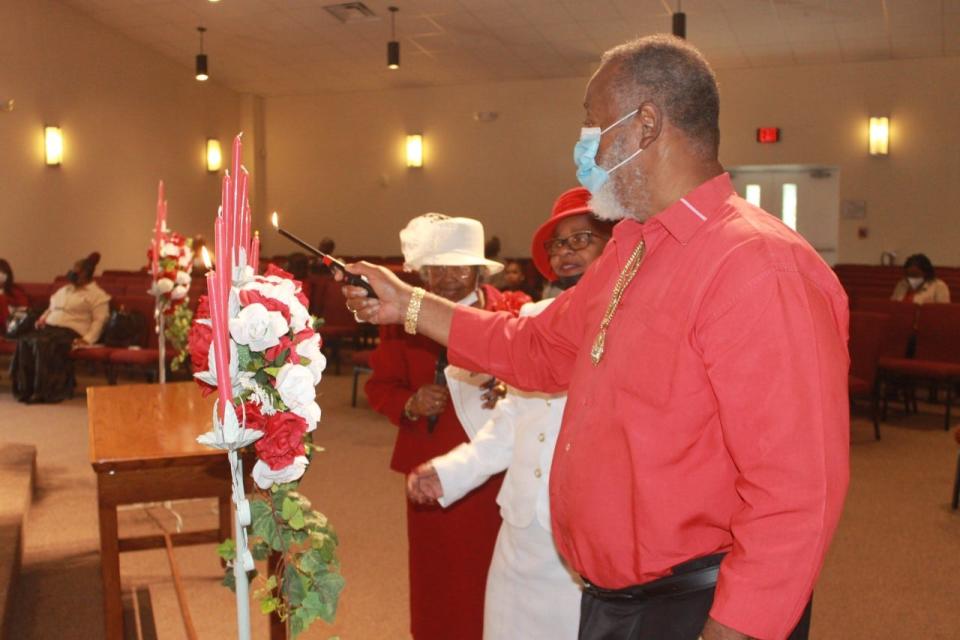 Bernard (Mr. Magic) Batie, right, lights a candle in honor of his deceased mother, Mary Hart, during the Senior Saints Day service held Sunday at First Missionary Baptist Church in southeast Gainesville. Hart was a longtime member of the church.
(Photo: Photo by Voleer Thomas/For The Guardian)