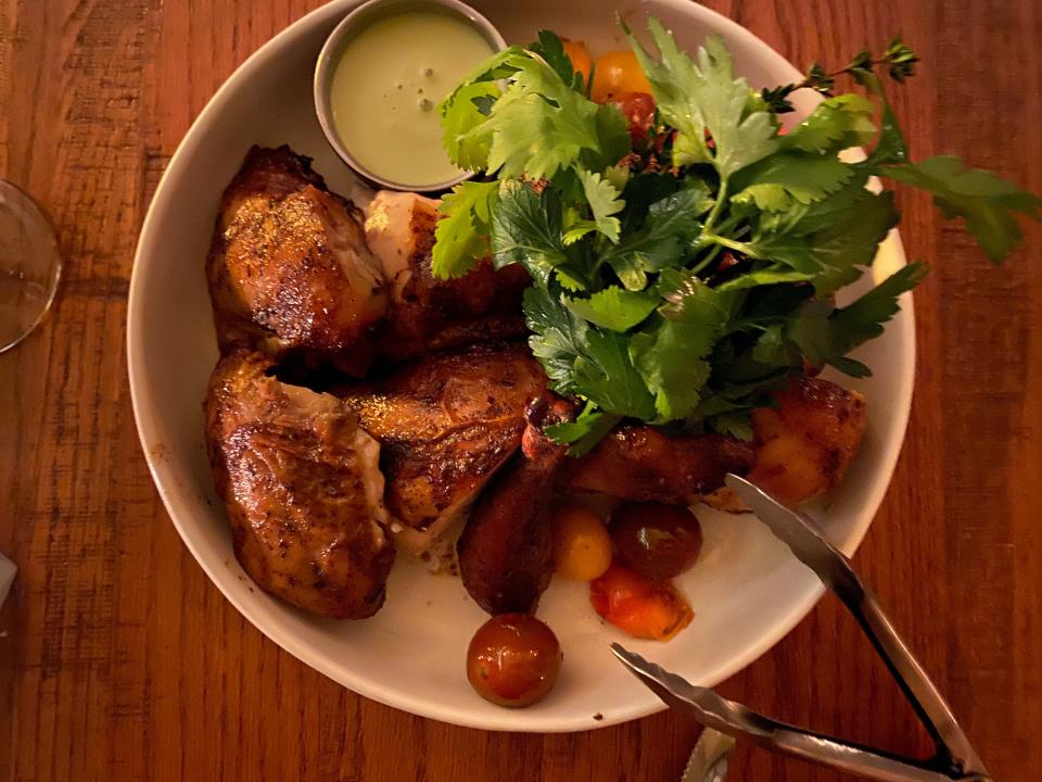 A dish of chicken, potatoes, and cherry tomatoes.