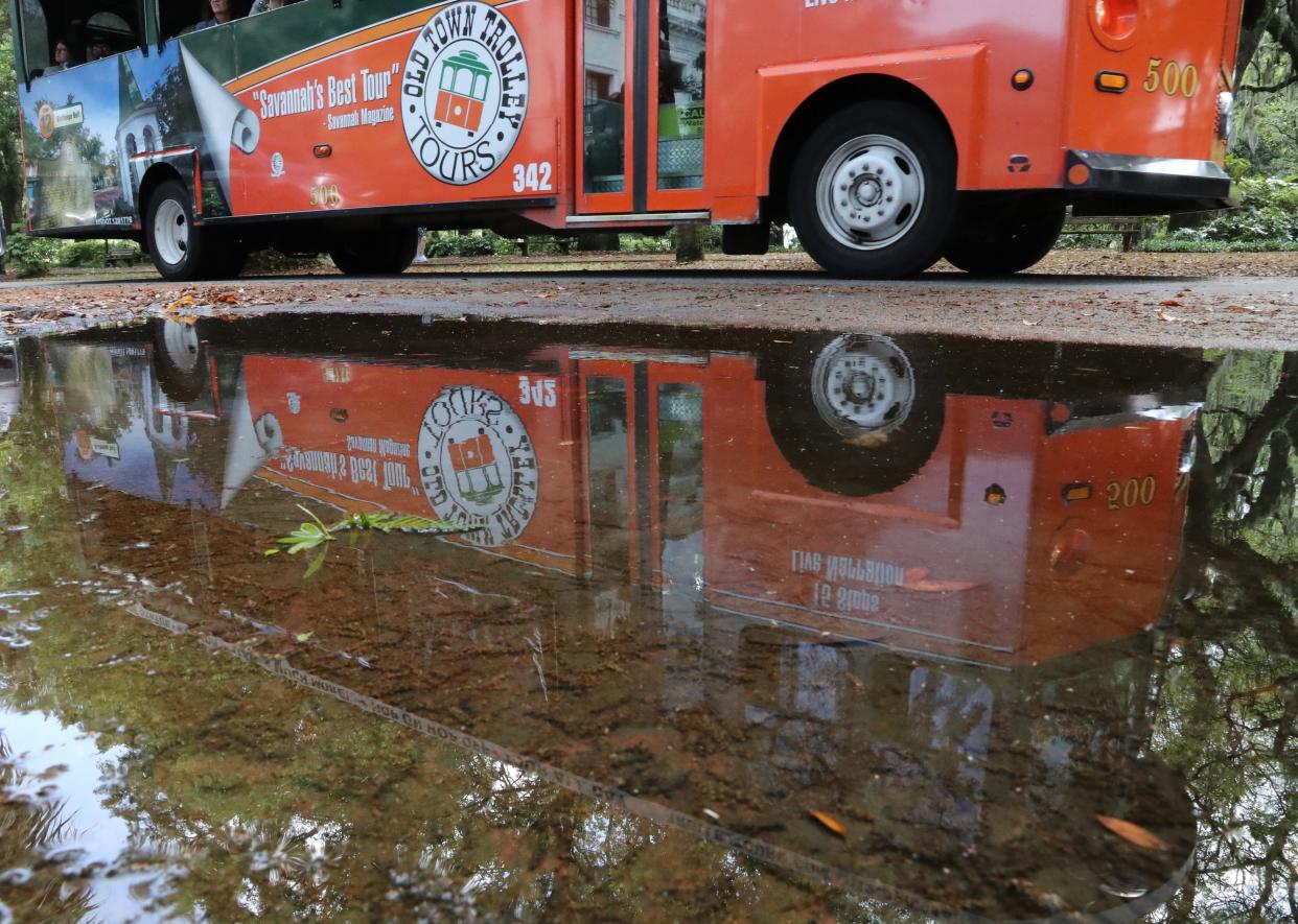 A trolley is reflected in a puddle left over from heavy rains on Thursday, April 11, 2024 near Forsyth Park.