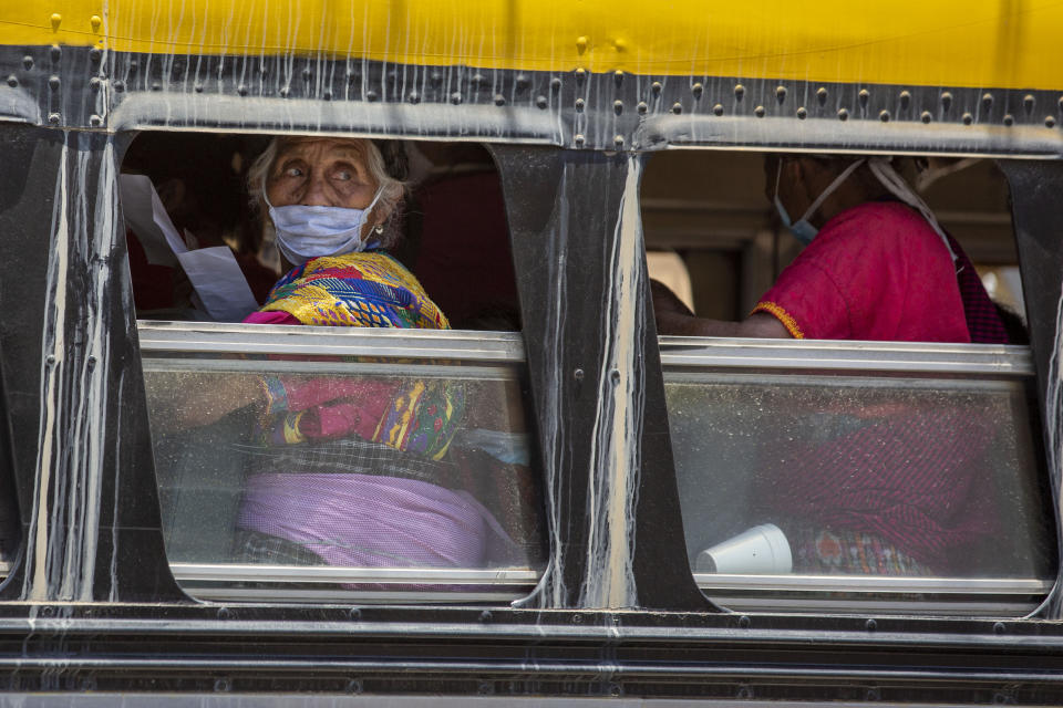 Women members of an organization of widows of bus drivers victims of violence, stand in a bus after being given food by officials of the Ministry of Social Development, in Guatemala City, Thursday, April 2, 2020. The Guatemalan government began to deliver food to people without income as a way to mitigate the spread of COVID-19. (AP Photo/Moises Castillo)