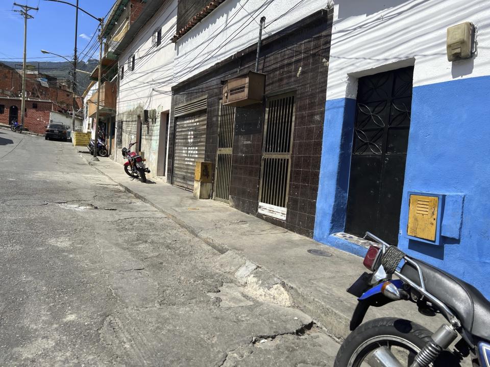 The second house from right to left, with a "No Parking" sign in Spanish on the door of its garage is the listed address of one of the startups involved in a massive corruption scandal that bilked billions of dollars in Venezuelan oil, and whose owner has never heard of the firm, at a working-class district in Caracas, Venezuela, Tuesday, March 28, 2023. The corporation, Walker International DW-LLC, is among 90 mostly unknown trading companies that together owed $10.1 billion as of Aug. 2022 to Venezuela’s state-owned oil giant Petroleos de Venezuela SA, according to internal records obtained by The Associated Press. (AP Photo/Regina Garcia Cano)
