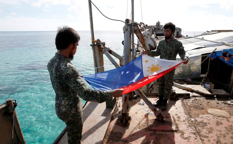 FILE PHOTO: Philippine Marines fold a Philippine national flag during a flag retreat at the BRP Sierra Madre, a marooned transport ship in the disputed Second Thomas Shoal