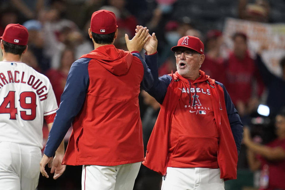 Los Angeles Angels designated hitter Shohei Ohtani (17) high-fives manager Joe Maddon after an 11-3 win over the Tampa Bay Rays in a baseball game in Anaheim, Calif., Monday, May 9, 2022. (AP Photo/Ashley Landis)