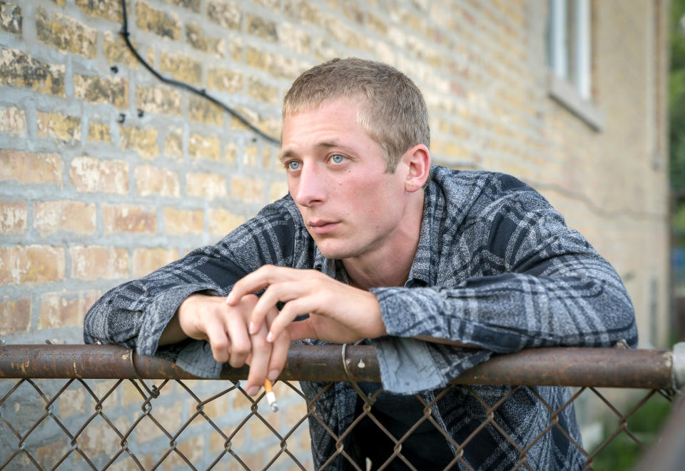 Man resting arms on a fence looking thoughtful. He's wearing a patterned shirt. Used for a TV show article