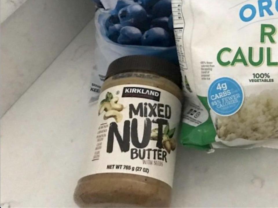 costco mixed nut butter on a white counter next to bags of frozen blueberries and riced cauliflower