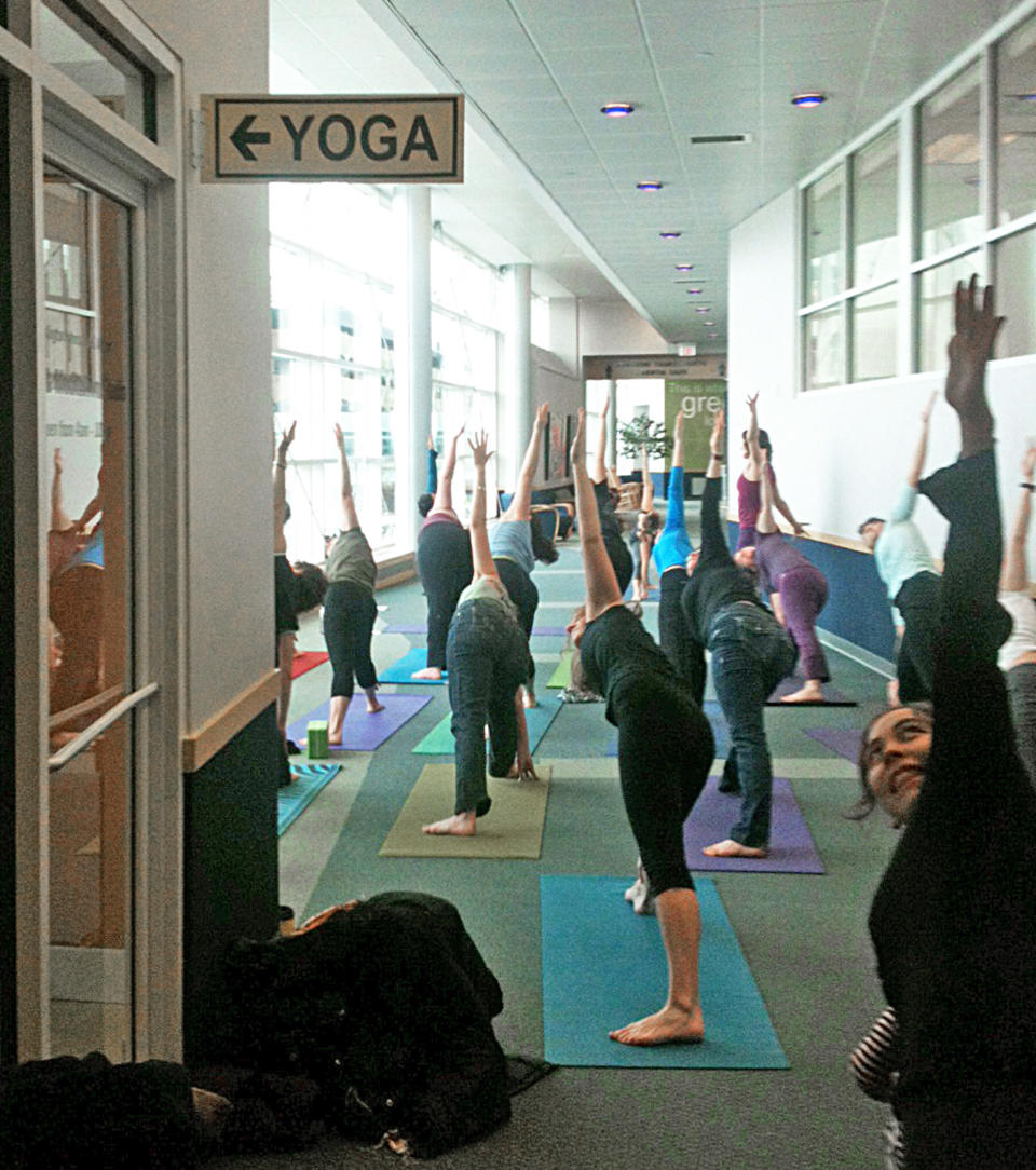 This Jan. 12, 2013 photo shows a local class does yoga at the Burlington International Airport in Burlington, Vt., to celebrate the grand opening of a yoga space for travelers. The airport is one of at least three airports offering a space for travelers to practice yoga while waiting for flights to make their trip more relaxing..(AP Photo/Lisa Rathke)