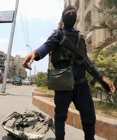 A masked policeman investigates the site of a car bomb attack on the convoy of Egyptian public prosecutor Hisham Barakat near his house at Heliopolis district in Cairo, Egypt, June 29, 2015. REUTERS/Mohamed Abd El Ghany