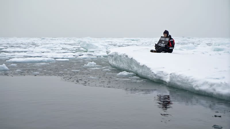 Environmental activist and campaigner Mya-Rose Craig holds a cardboard sign reading “youth strike for climate” in the middle of the Arctic Ocean