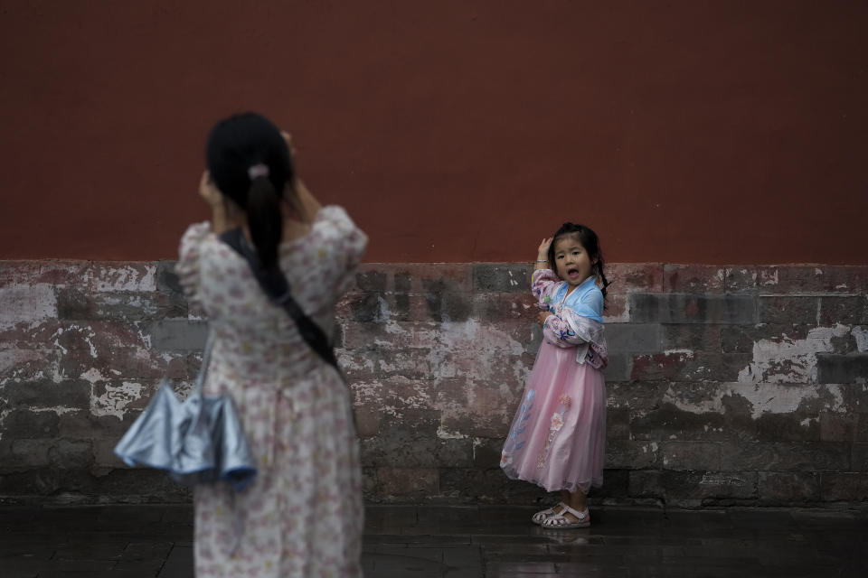 A child wearing a traditional costume poses for a photo against a wall of the Garden of the Palace of Compassion and Tranquility, known as Dining gong huayuan, at the Forbidden City in Beijing on Thursday, July 13, 2023. (AP Photo/Andy Wong)