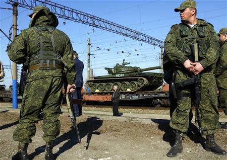 Armed Russian servicemen stand guard as Russian tanks arrive at a train station in the Crimean settlement of Gvardeiskoye near the Crimean city of Simferopol March 31, 2014. REUTERS/Yannis Behrakis