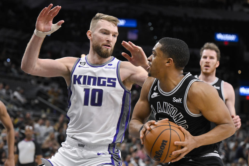 San Antonio Spurs' Keldon Johnson, right, drives against Sacramento Kings' Domantas Sabonis during the second half of an NBA basketball game, Wednesday, Feb. 1, 2023, in San Antonio. Sacramento won 119-109. (AP Photo/Darren Abate)