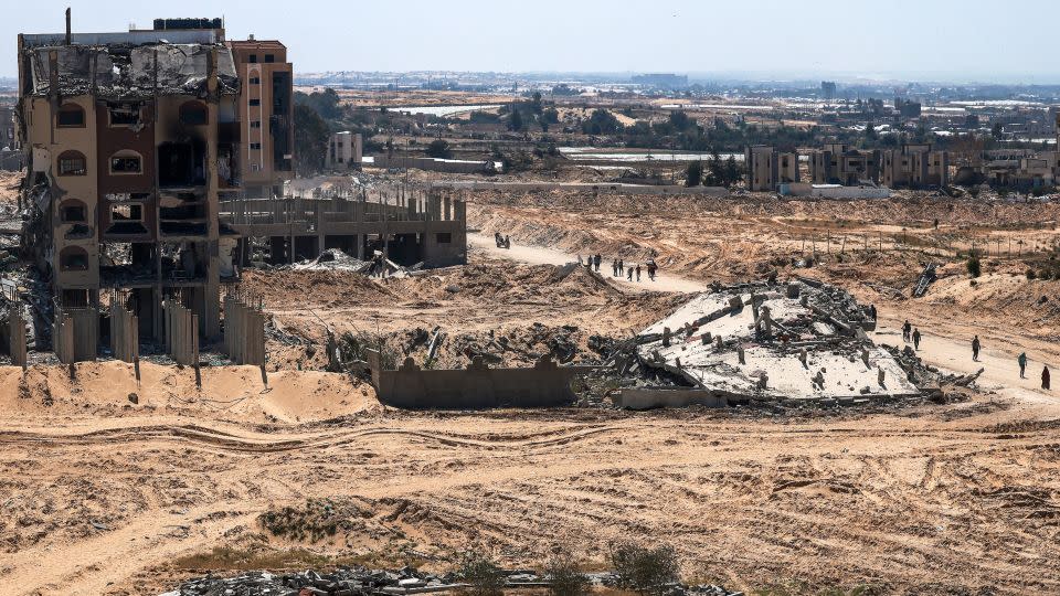 People walk past damaged and destroyed buildings in Khan Yunis on April 7, after Israel pulled its ground forces out of the area. - Mohammed Abed/AFP/Getty Images