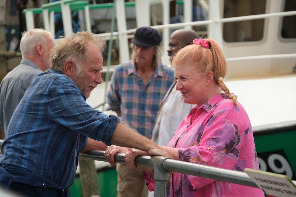  Beyond Paradise season 2 episode 3: Jaime (Danny Webb) and Margo (Felicity Montagu) stand on either side of a railing at the harbour, looking into each other's eyes. Margo is smiling. 