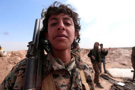 A young Syrian Democratic Forces fighter poses for a picture with his weapon north of Raqqa city, Syria. REUTERS/Rodi Said