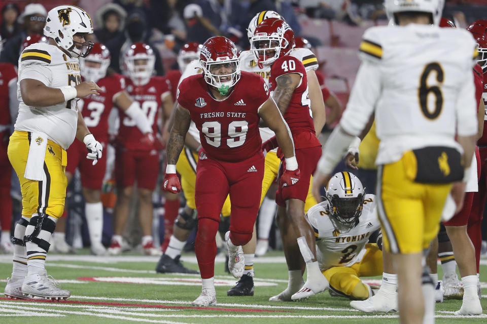 Fresno State defensive end David Perales celebrates a third-down stop, as Wyoming quarterback Andrew Peasley, right, stands nearby during the first half of an NCAA college football game in Fresno, Calif., Friday, Nov. 25, 2022. (AP Photo/Gary Kazanjian)
