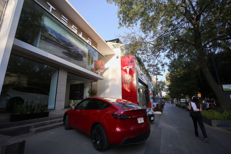 Una mujer camina junto a un concesionario de Tesla en Ciudad de México