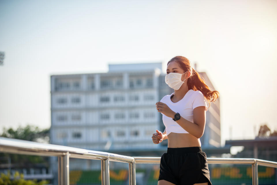 Asian Young fitness sport woman running  and she wears a  mask for protective Dust and pollution on city