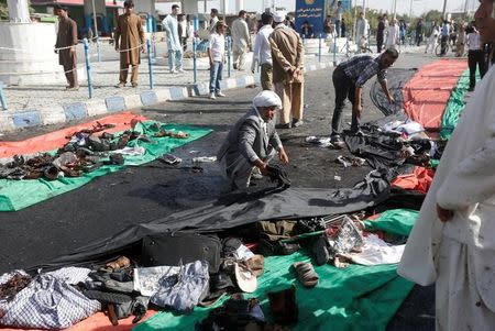 Afghan men remove the clothes of victims after a suicide attack in Kabul, Afghanistan July 23, 2016. REUTERS/Omar Sobhani