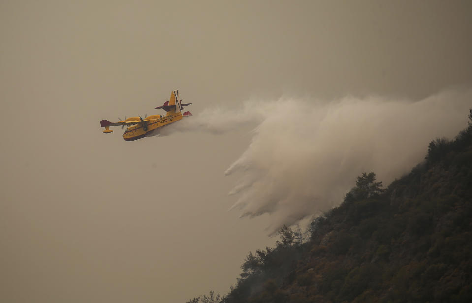 A Spanish firefighting plane pours water on a fire near the Kemerkoy Power Plant, a coal-fueled power plant, in Milas, Mugla in southwest Turkey, Thursday, Aug. 5, 2021. A wildfire that reached the compound of a coal-fueled power plant in southwest Turkey and forced evacuations by boats and cars, was contained on Thursday after raging for some 11 hours, officials and media reports said. (AP Photo/Emre Tazegul)