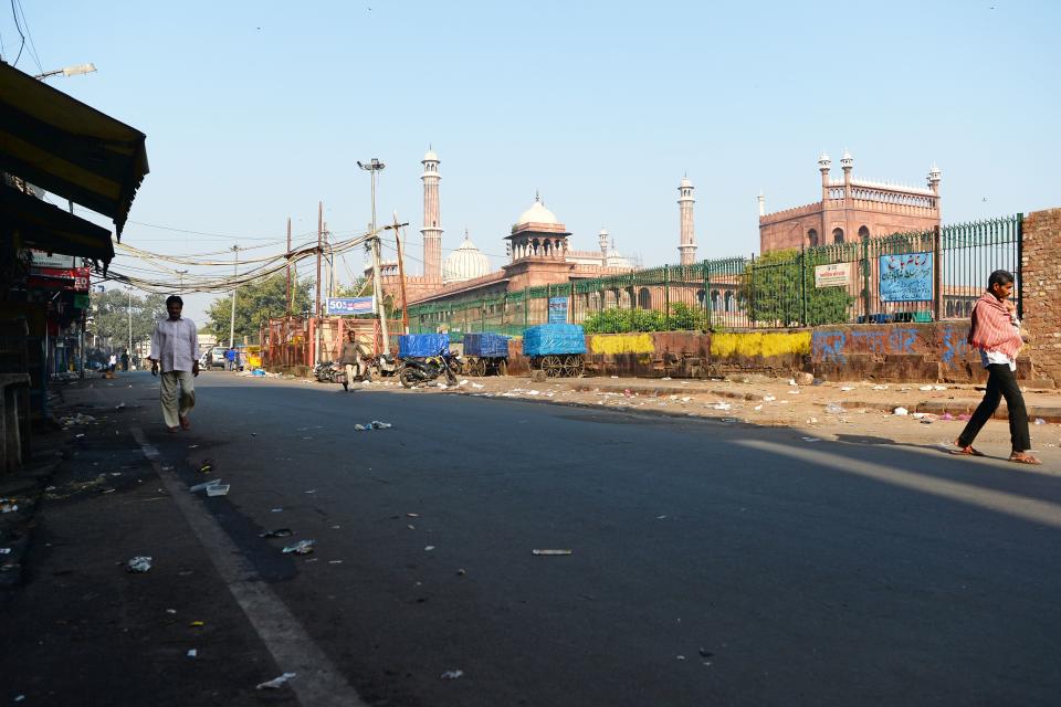 People walk through a partially empty road during a one-day Janata (civil) curfew imposed amid concerns over the spread of the COVID-19 novel coronavirus, near Jama Masjid mosque in the old quarters of New Delhi on March 22, 2020. (Photo by Sajjad HUSSAIN / AFP) (Photo by SAJJAD HUSSAIN/AFP via Getty Images)